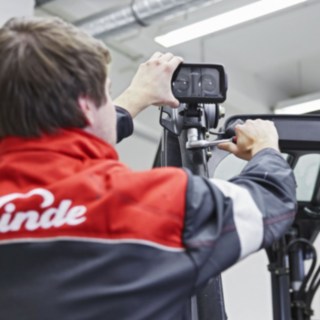 Un mecanic Linde Material Handling atașează un sistem Linde BlueSpot la plafonul unui stivuitor.