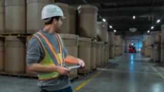 Angajații din depozit poartă vesta reflectorizantă interactivă de la Linde Material Handling în depozitul întunecos