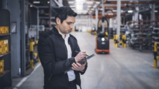 Un angajat al Linde Material Handling se află în depozit și își ia notițe pe tabletă.