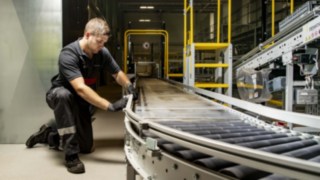 Un tehnician de service de la Linde MH repară un transportor