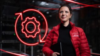 O angajată a companiei Linde Material Handling într-un depozit, cu simbolul LED roșu al unei roți dințate în fundal.