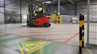 Depozitul Heineken cu stivuitorul electric E80 și simbol de avertizare pe podeaua depozitului
