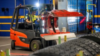 Un angajat Michelin Tyre PLC prinde o stivă de anvelope cu o clemă de anvelope pe Linde E20.