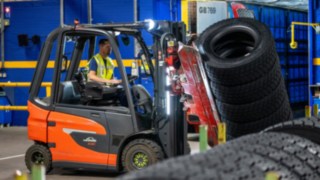 Un angajat Michelin Tyre PLC prinde o stivă de anvelope cu o clemă montată pe stivuitor.