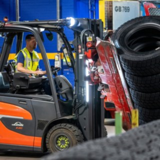 Un angajat Michelin Tyre PLC prinde o stivă de anvelope cu o clemă montată pe stivuitor.