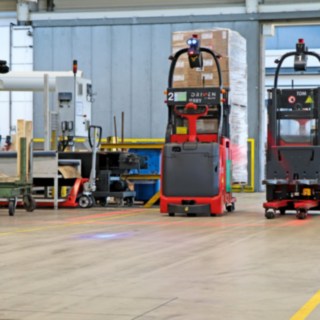 Doi transpaleți pentru înălțimi mari de ridicare L-MATIC transportă mărfurile între linia de ambalare și depozitul intermediar.