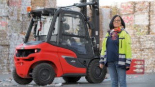 O femeie stă în fața unui stivuitor în incinta fabricii