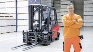 Un bărbat cu brațele încrucișate stă într-o hală de depozitare. Un motostivuitor Linde este în fundal. 