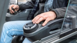 Un operator controlează un stivuitor Linde cu o singură mână.