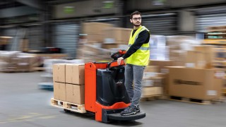 Linde e-driver permite operatorului să controleze toate funcțiile stivuitorului cu o singură mână, fără a pune presiune pe coloana vertebrală. Un transpalet pentru ridicare la înălțimi reduse Linde T20 se deplasează printr-un depozit, operatorul stă într-o poziție de 45 de grade