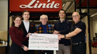 Donație de la Staplercup hilft e. V. către Aschaffenburger Kinderträume Cinci persoane stau împreună și țin în mână un cec mare cu o sumă de 10.000 de euro de la Linde către Aschaffenburger Kinderträume.