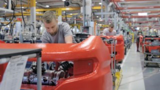 Conceptul nostru de platformă cu montaj mixt permite conservarea eficientă a resurselor. O serie de mecanici din fabrică lucrează la stivuitoarele Linde.